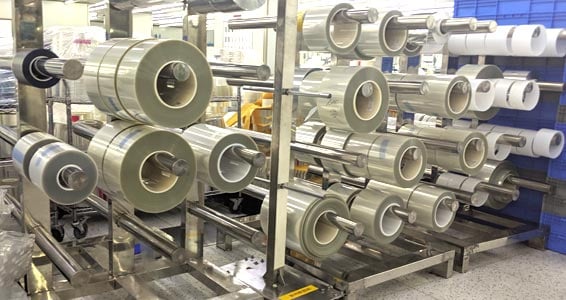 rack with rolls of optically clear adhesives and materials housed in a clean room environment